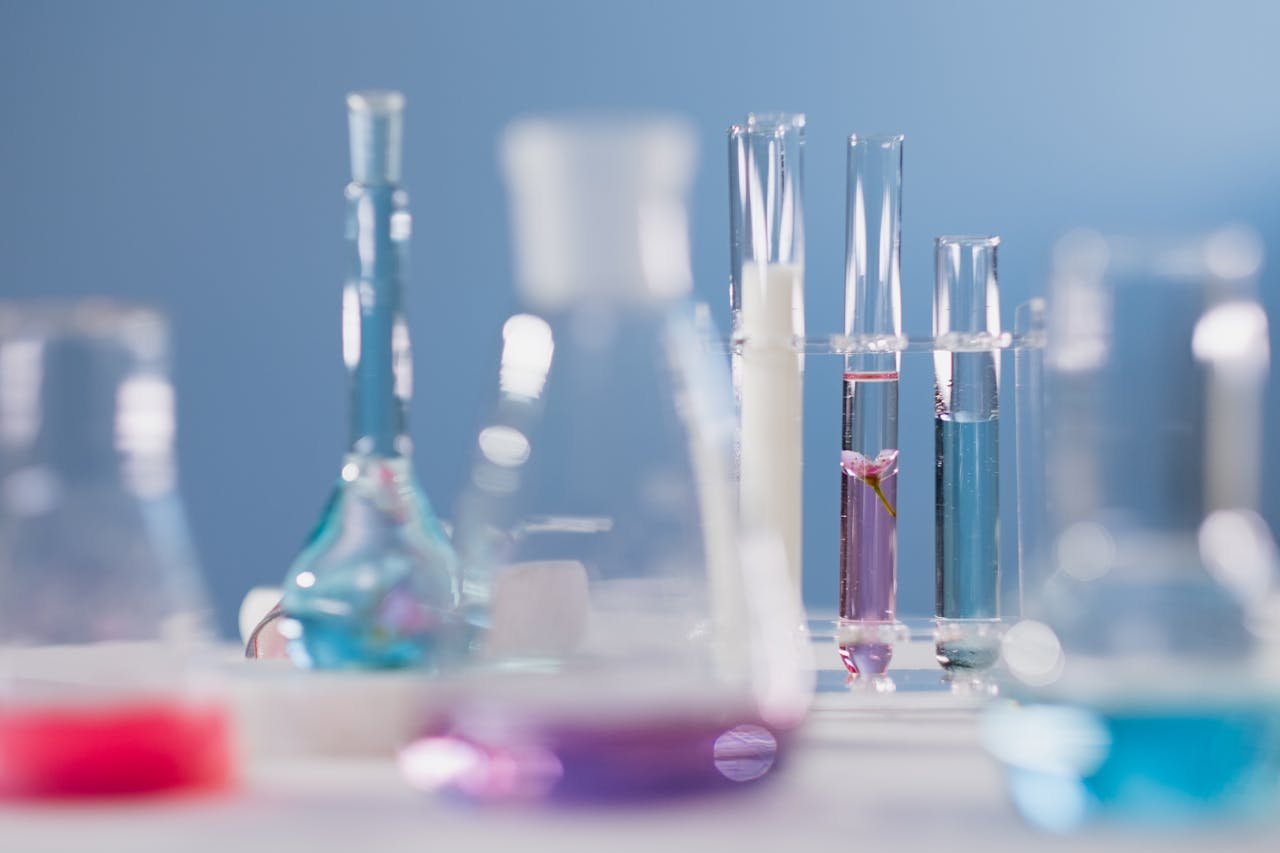 Close-up of various glassware with colorful liquids in a lab setting.