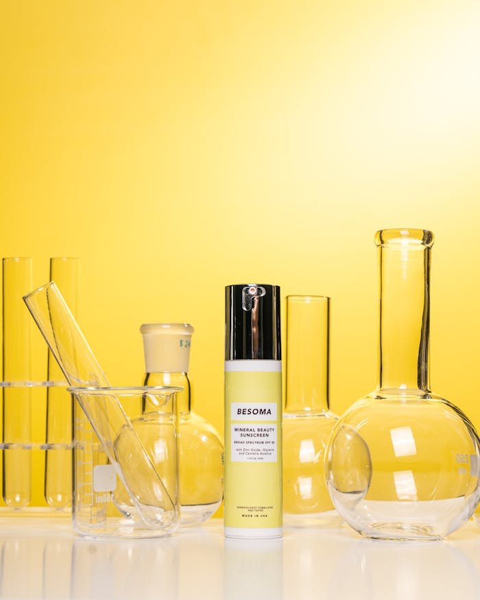 Beauty cosmetic amidst laboratory glassware on a vibrant yellow background.